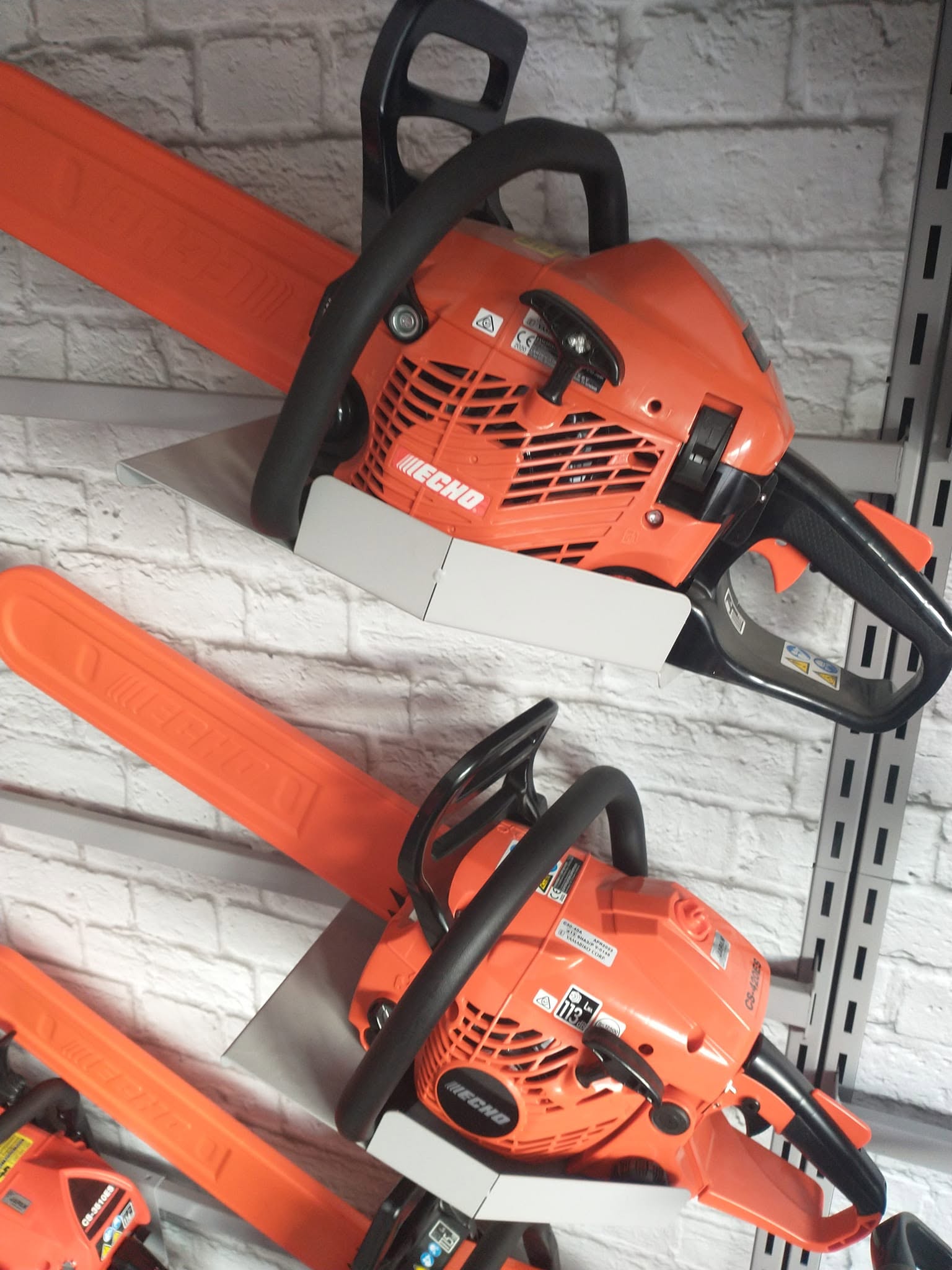 Echo petrol chainsaws on wall mount display racks at RM Lawnmowers