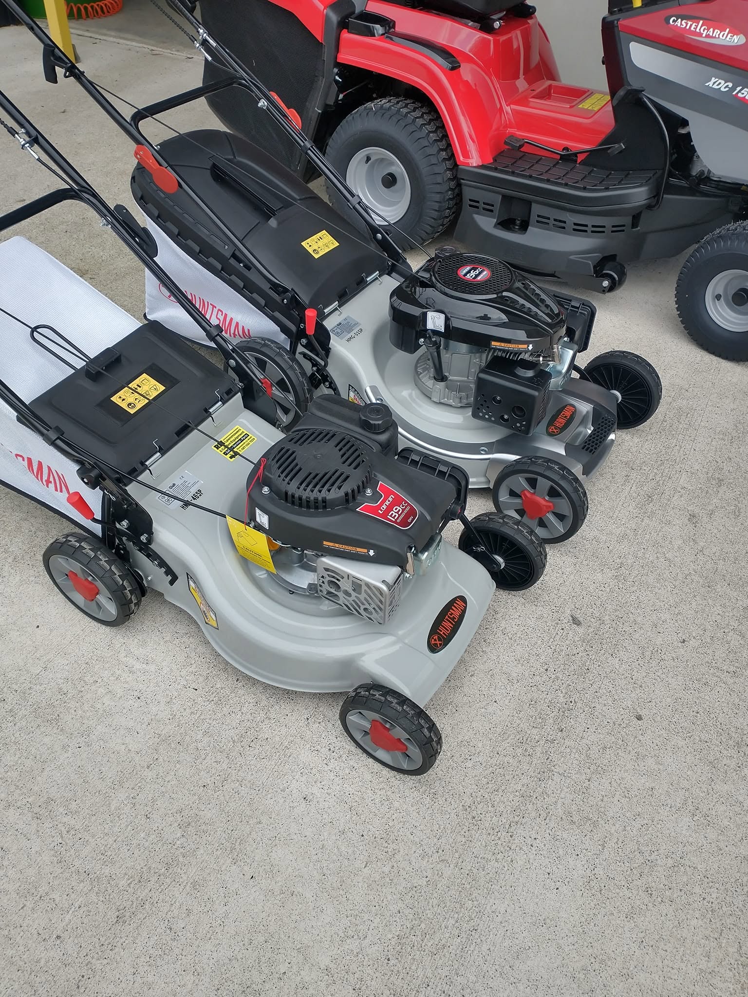 Huntsman HM-46SP push lawnmowers with Loncin engines parked outside showroom