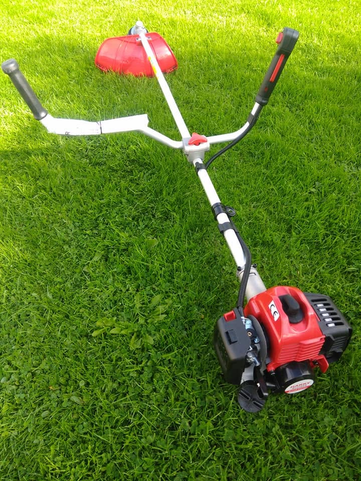 Petrol straight-shaft brushcutter with bike handles on lawn
