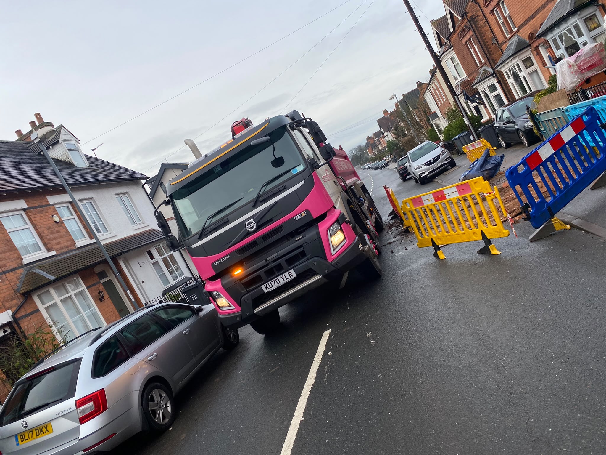 Little Miss Grab pink truck clearing utilities and road excavation on a residential street