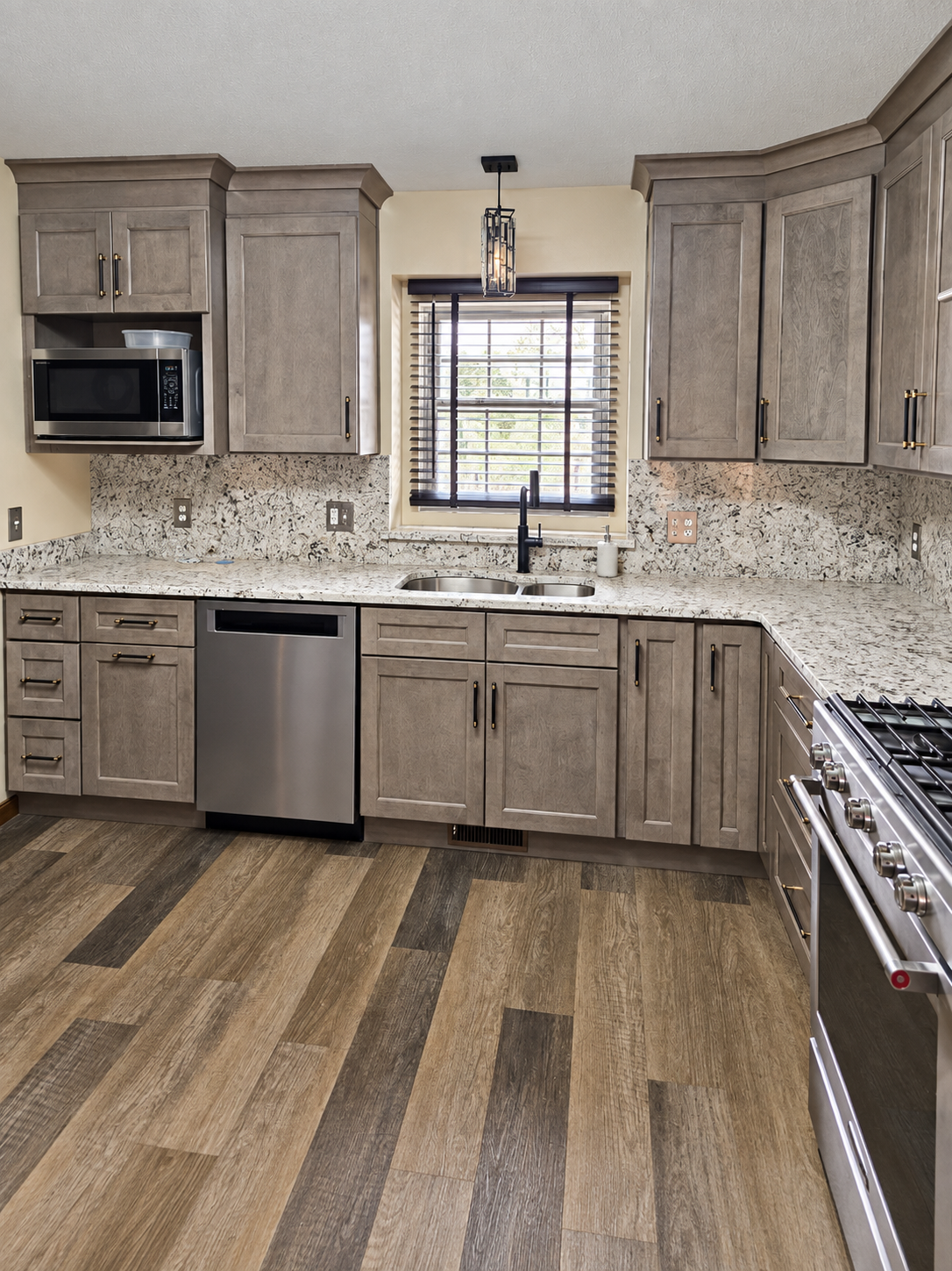 Finished kitchen remodel with custom gray cabinetry, granite countertops, and luxury vinyl plank flooring