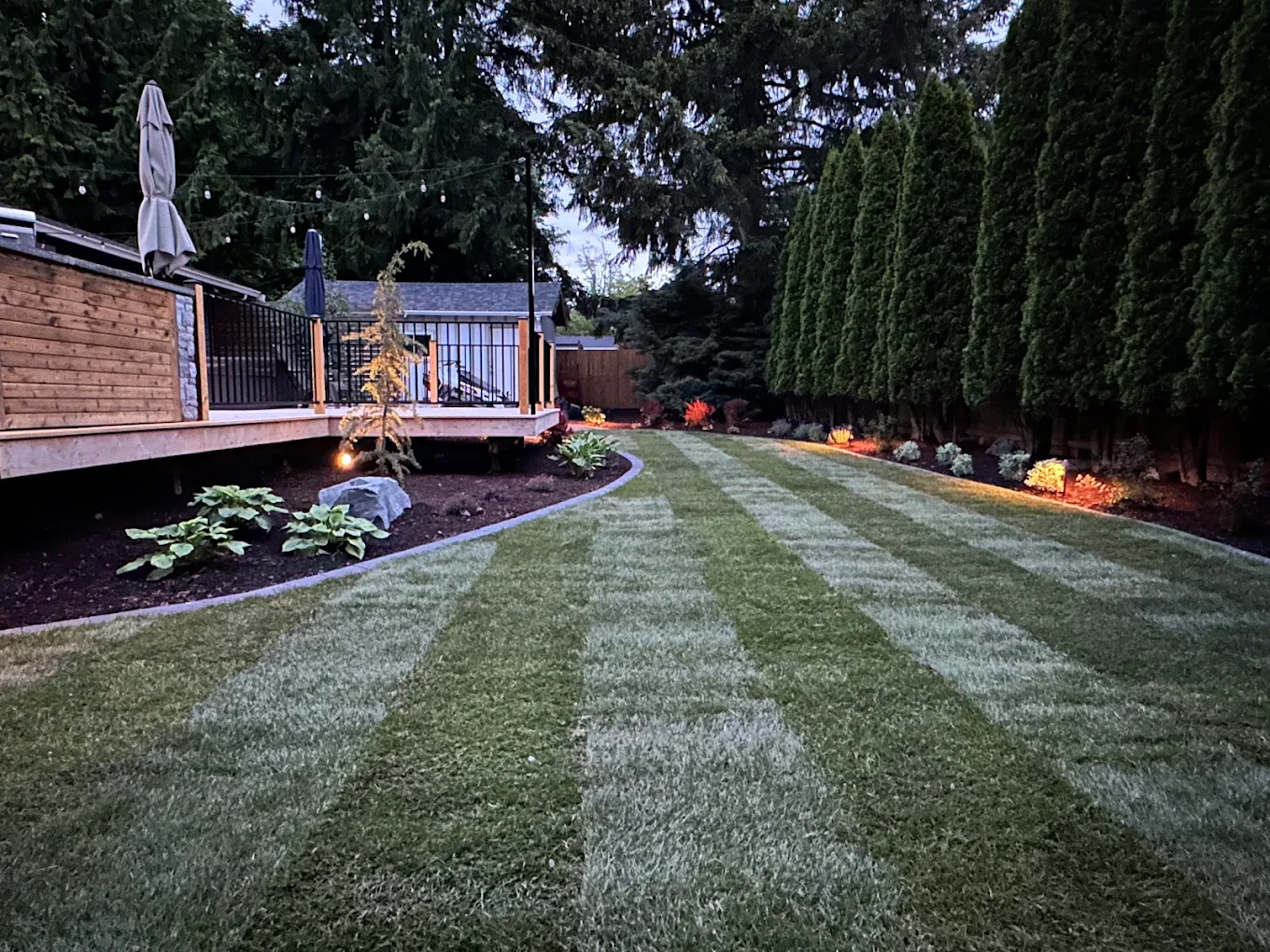 Landscaped backyard with paver patio, retaining wall, and sprinkler system in the Pacific Northwest