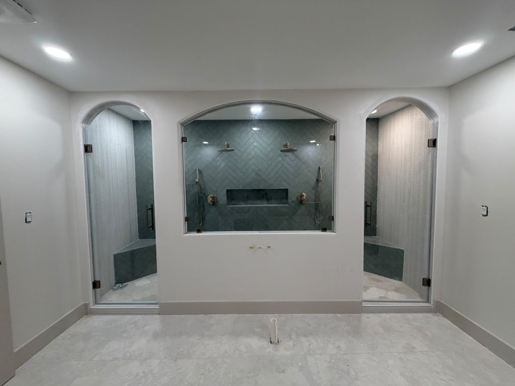 Custom arched glass shower doors with center viewing window and dual shower heads