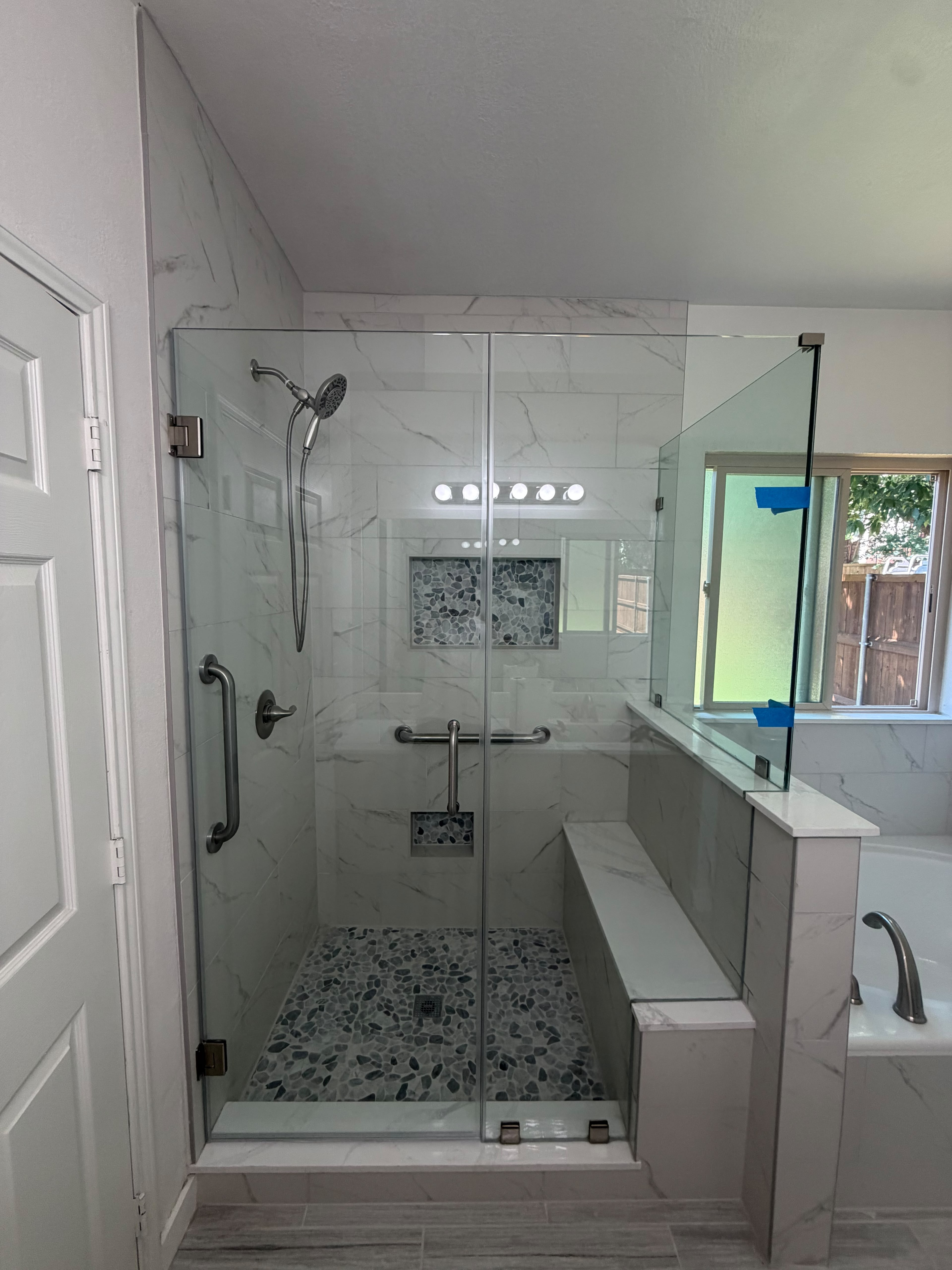 Frameless glass shower enclosure with built-in bench and pebble tile floor