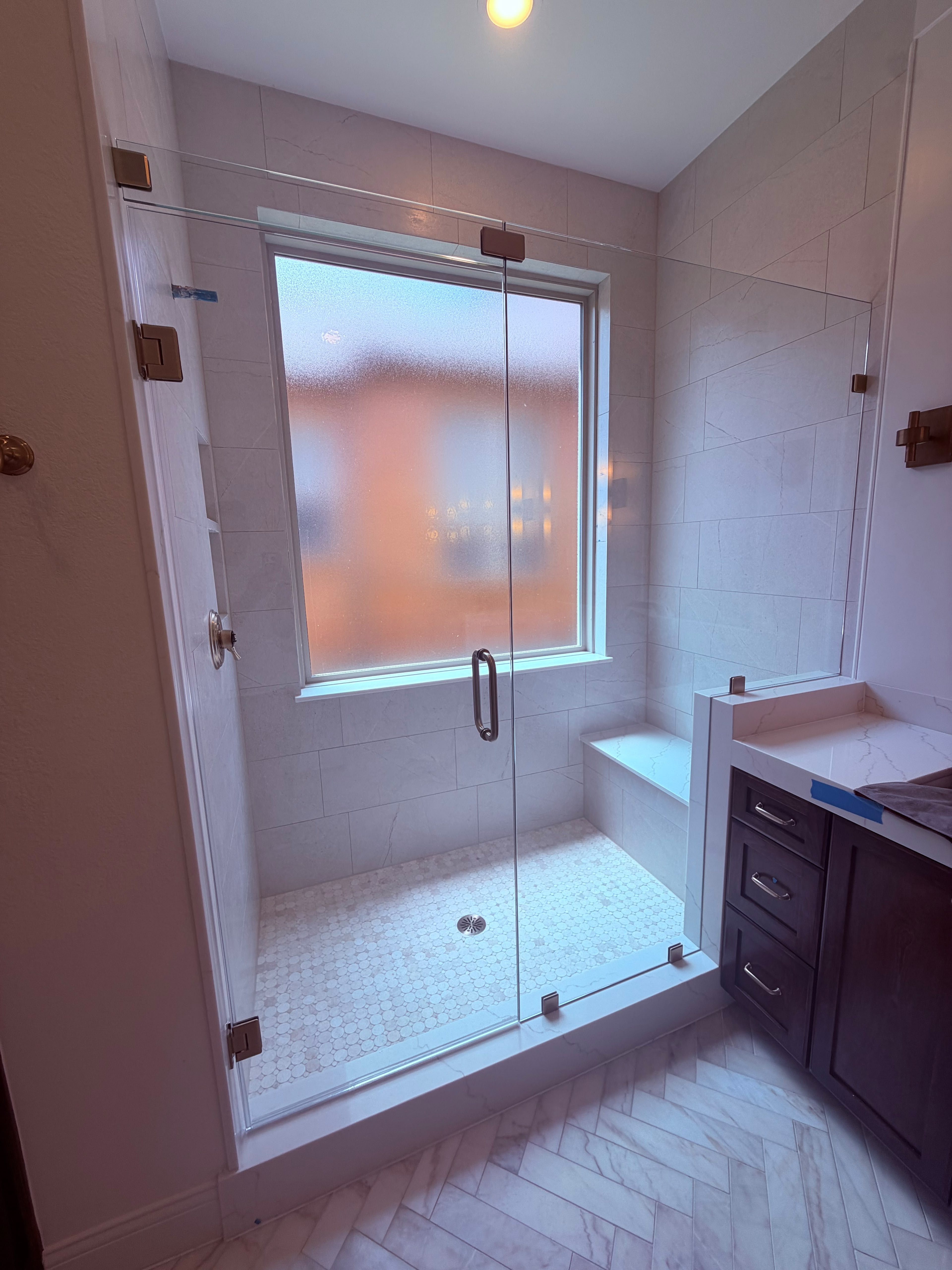 Frameless glass shower door with oil-rubbed bronze hardware and built-in bench