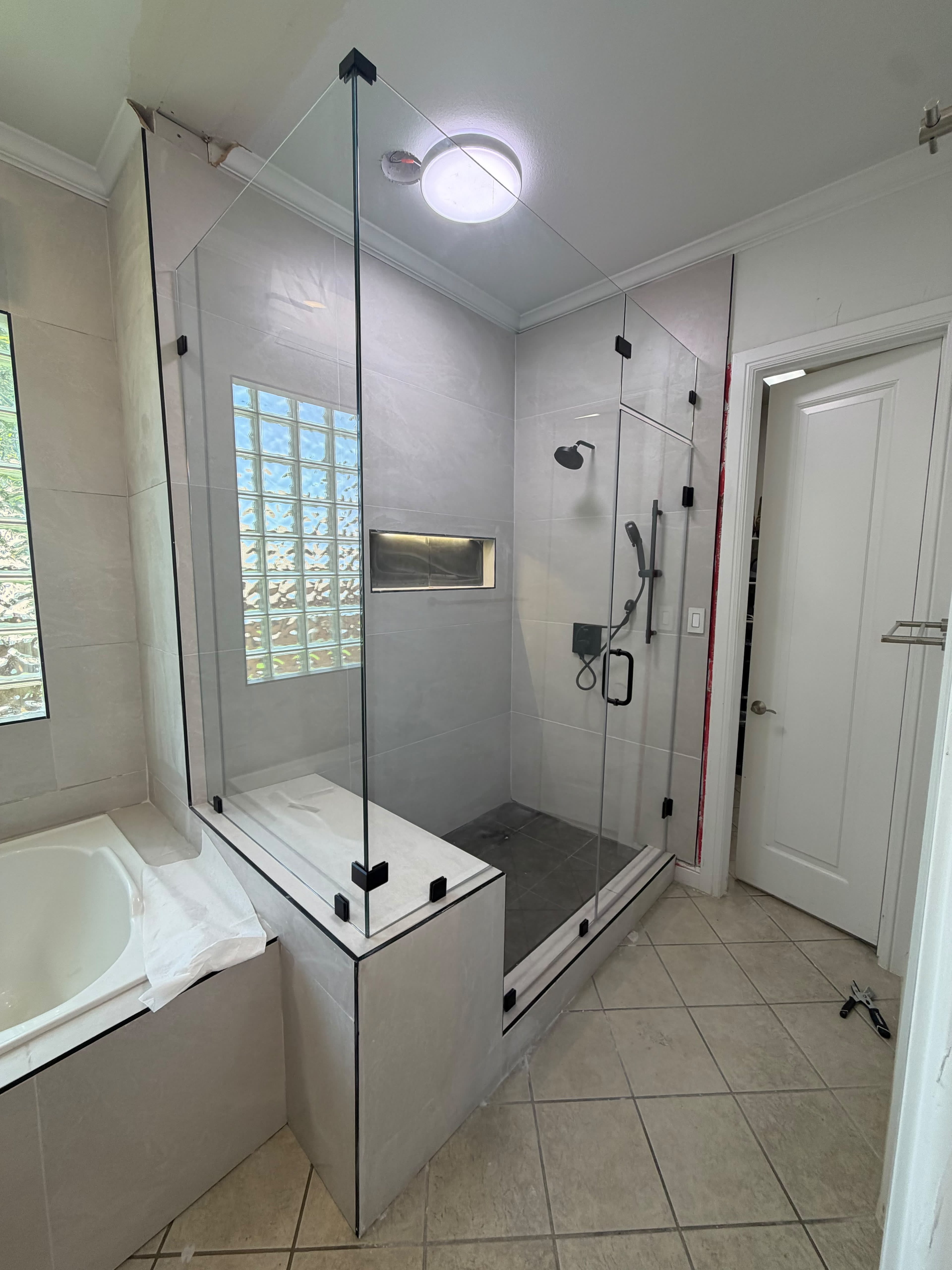 Frameless glass shower enclosure with tiled bench seat and matte black clips