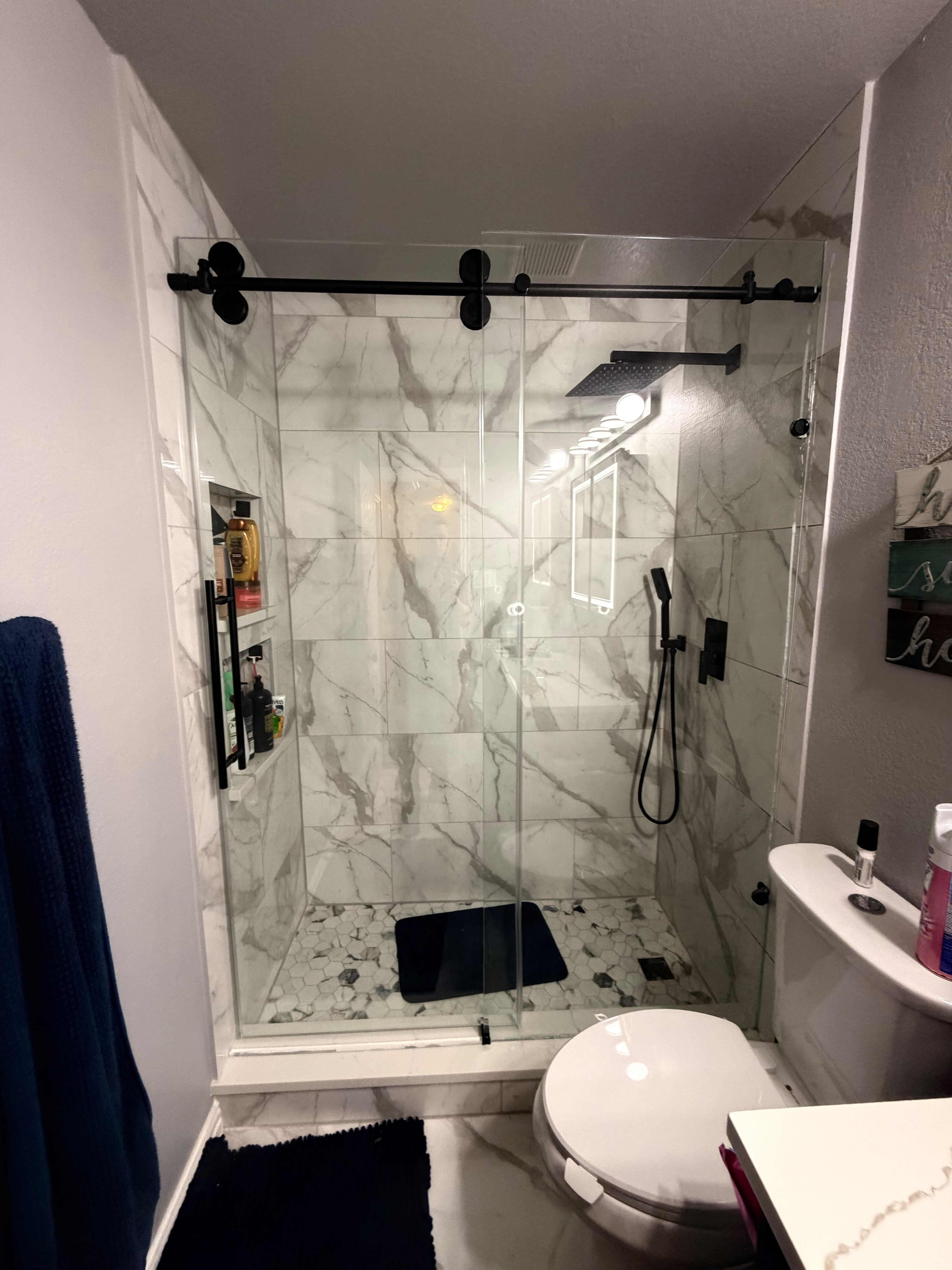 Modern sliding glass barn-door shower enclosure with matte black roller hardware