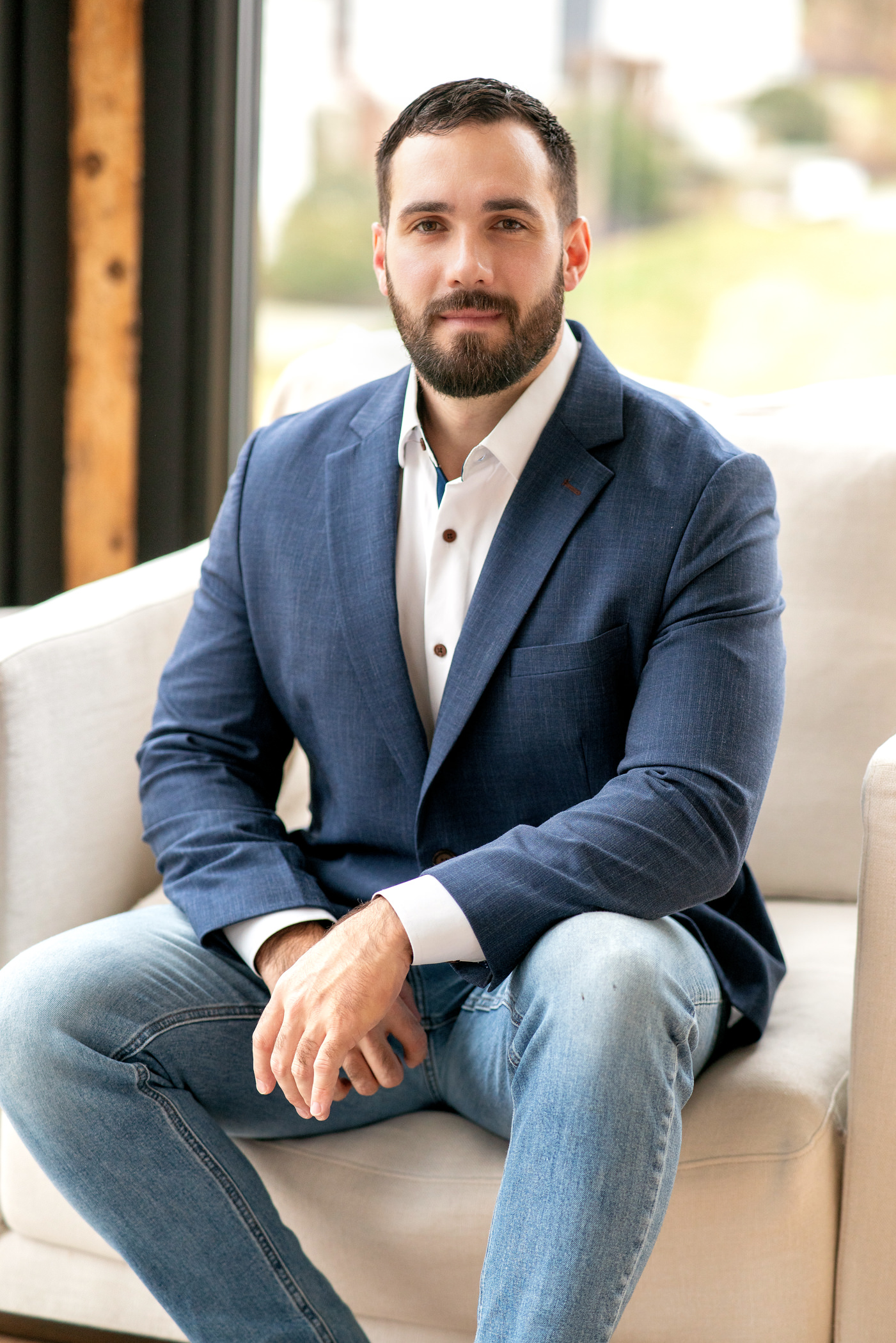Male founder and entrepreneur in navy blazer seated in modern lounge