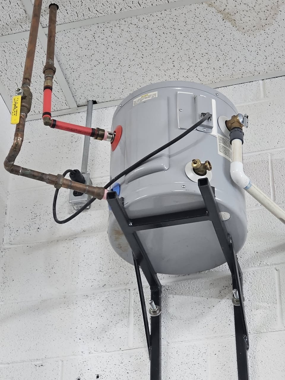 Water heater mounted high on a steel wall bracket near the ceiling, Johnson City, TN