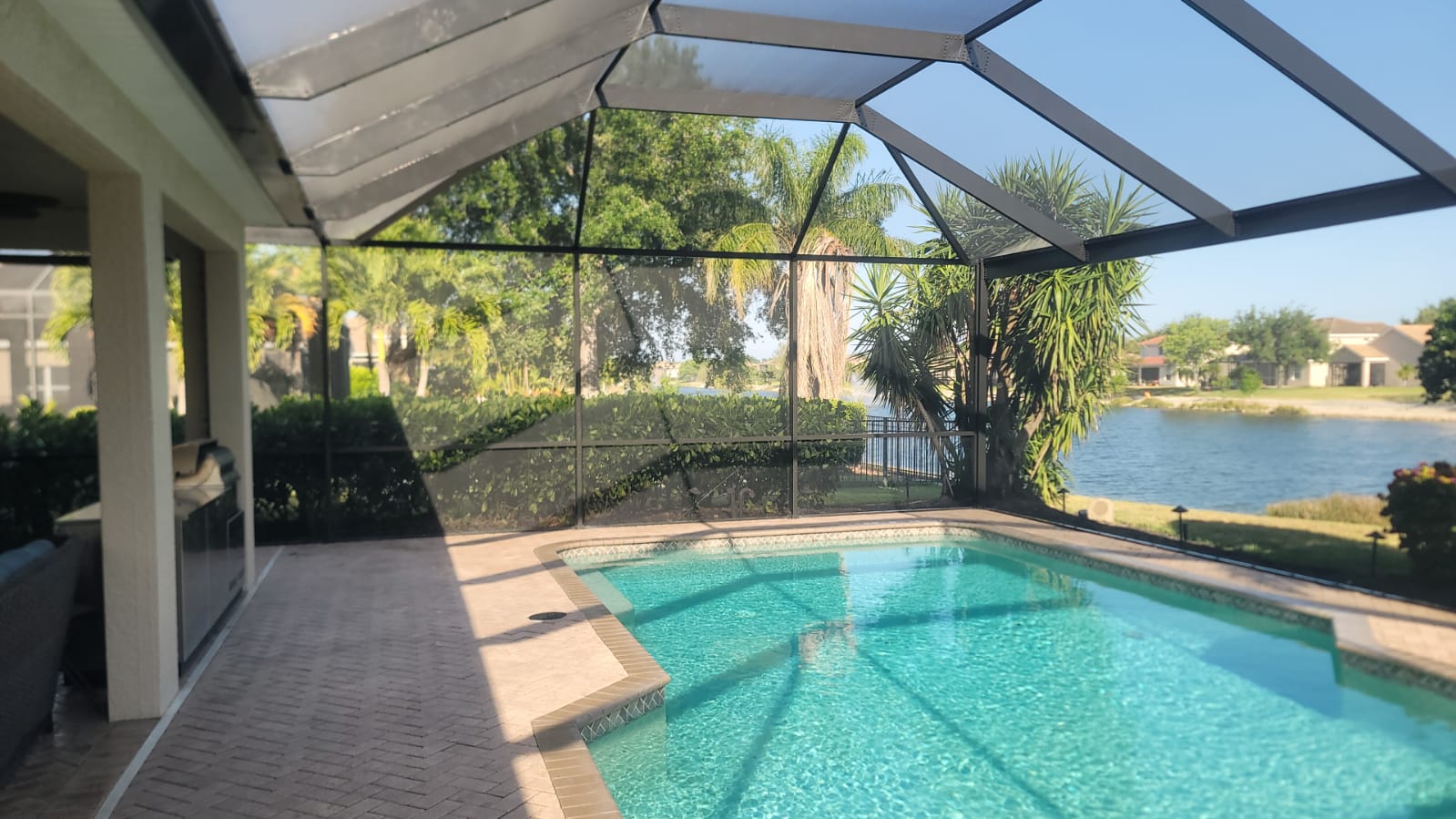Finished swimming pool under custom screen enclosure with clean deck and palm landscaping in Southwest Florida