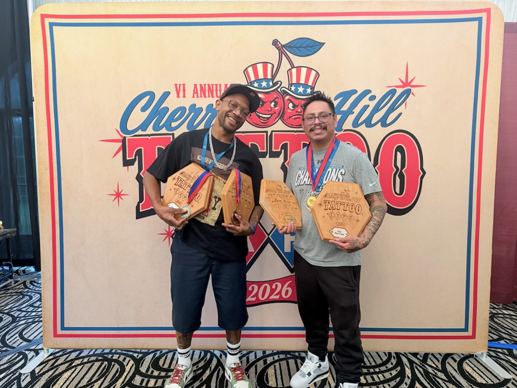 Matthew Evans and Max Ramirez holding multiple award plaques at the Cherry Hill Tattoo Expo