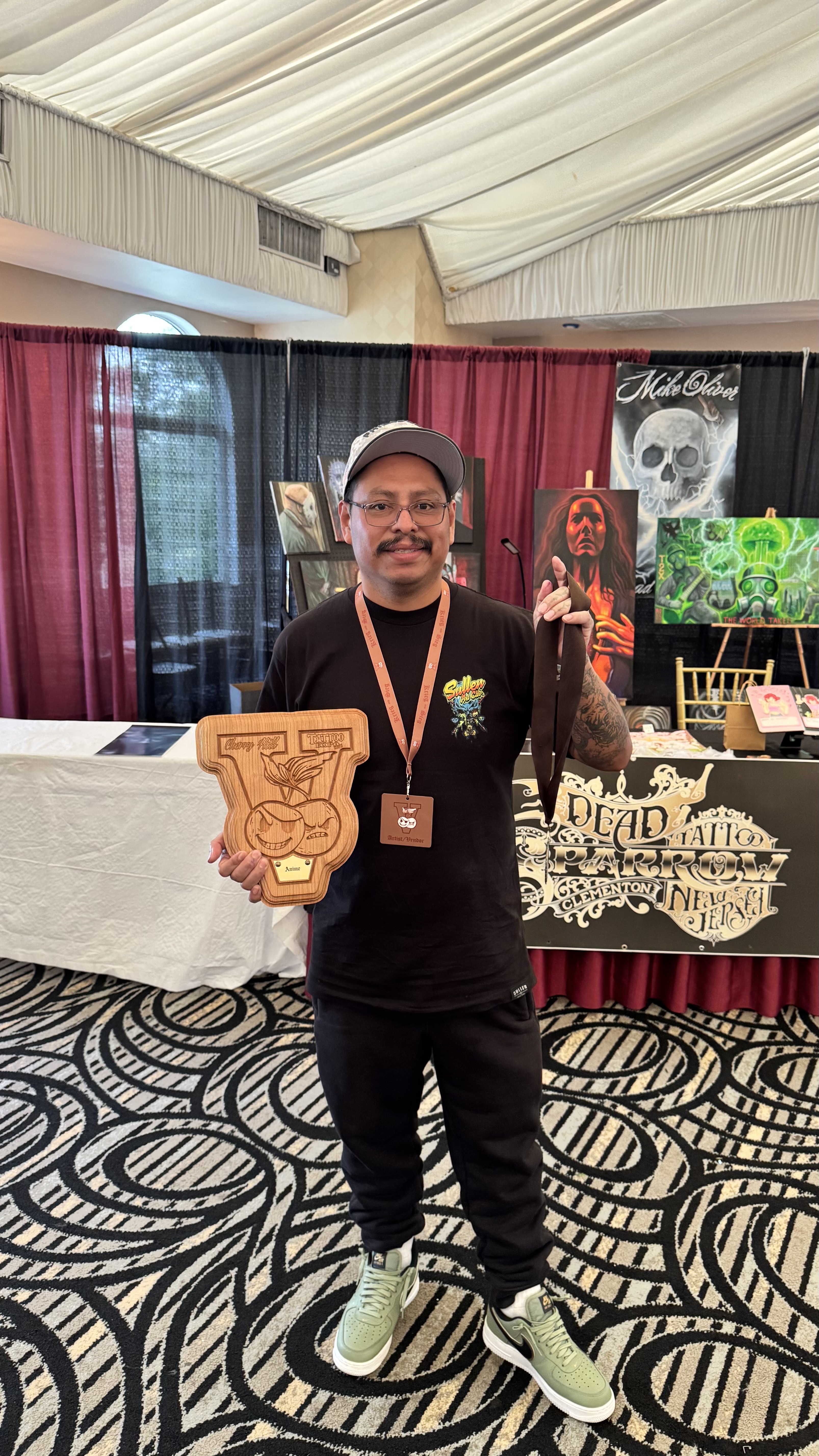 Max Ramirez of Drop 'N Ink Tattoo Studio holding his award plaque