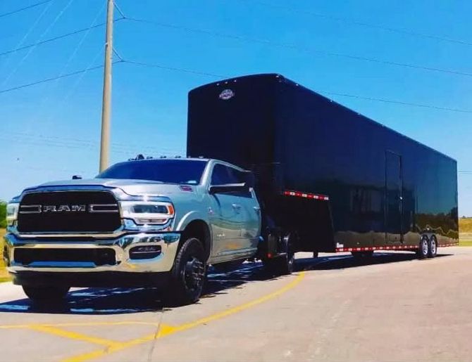 Pickup truck pulling an enclosed moving trailer on a sunny road