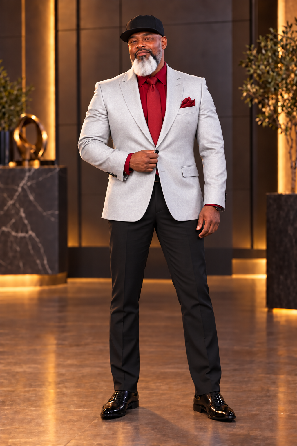 Author A. Rackstraw in a buttoned silver jacket, red shirt, and red tie, standing in a confident power pose