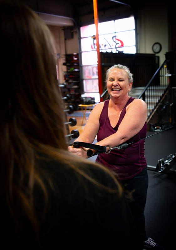 Smiling client training with her coach at 360 Fitness Red Deer