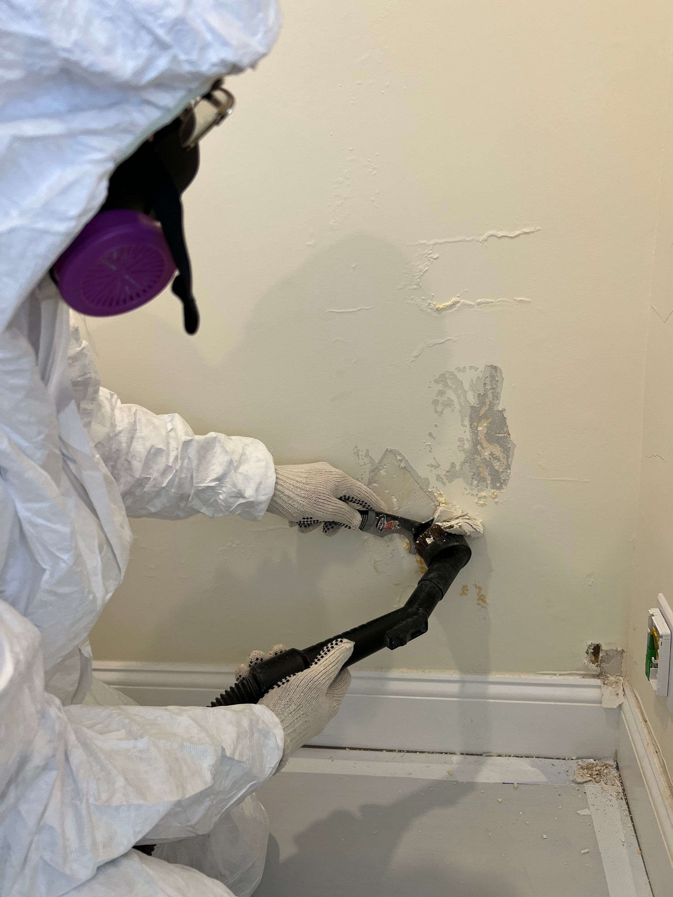Promore Mold Remediation Specialist Scraping Masonry Wall in Full Tyvek Suit