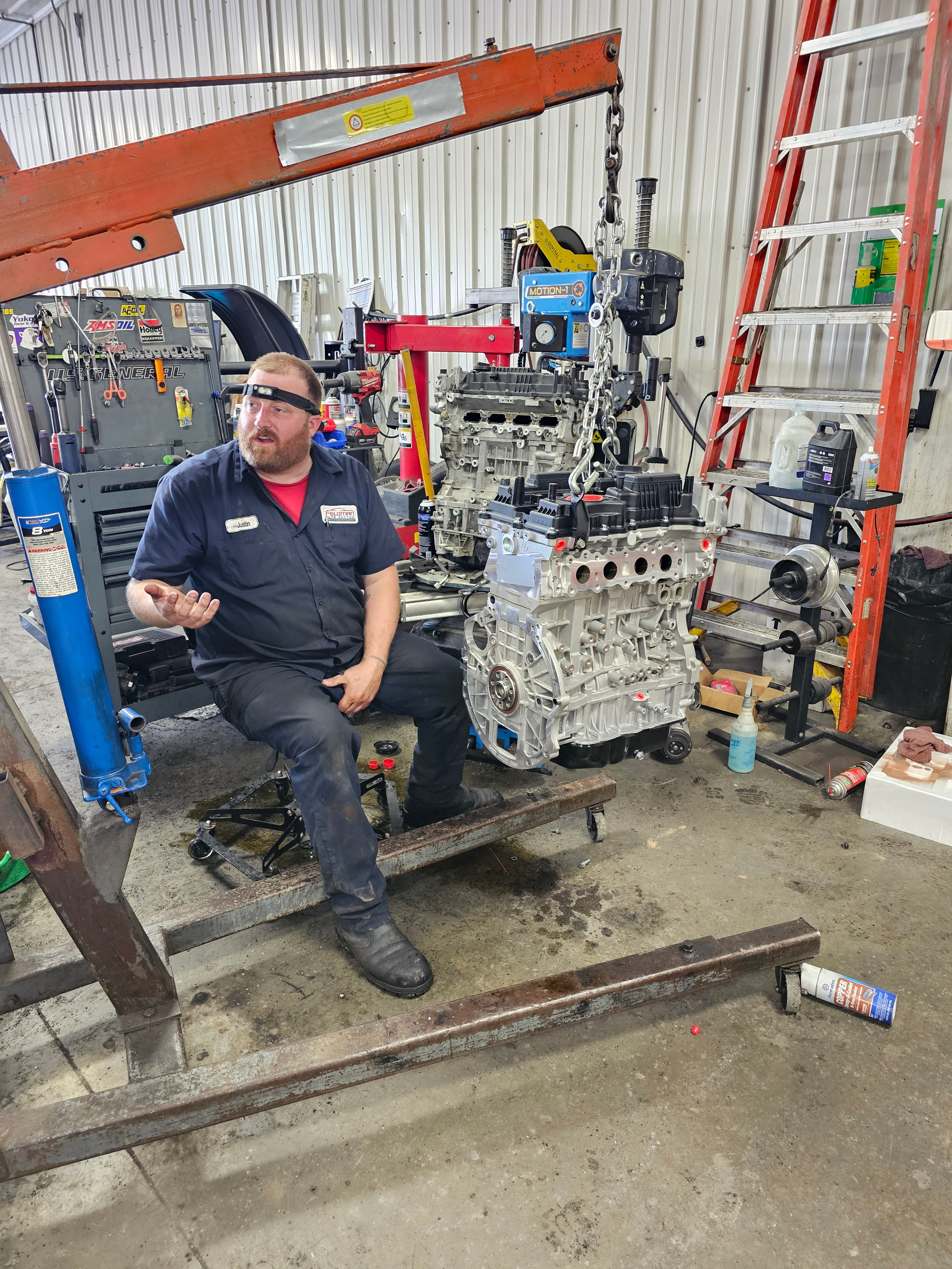 Justin, technician at Feldman Auto Center with engine on hoist