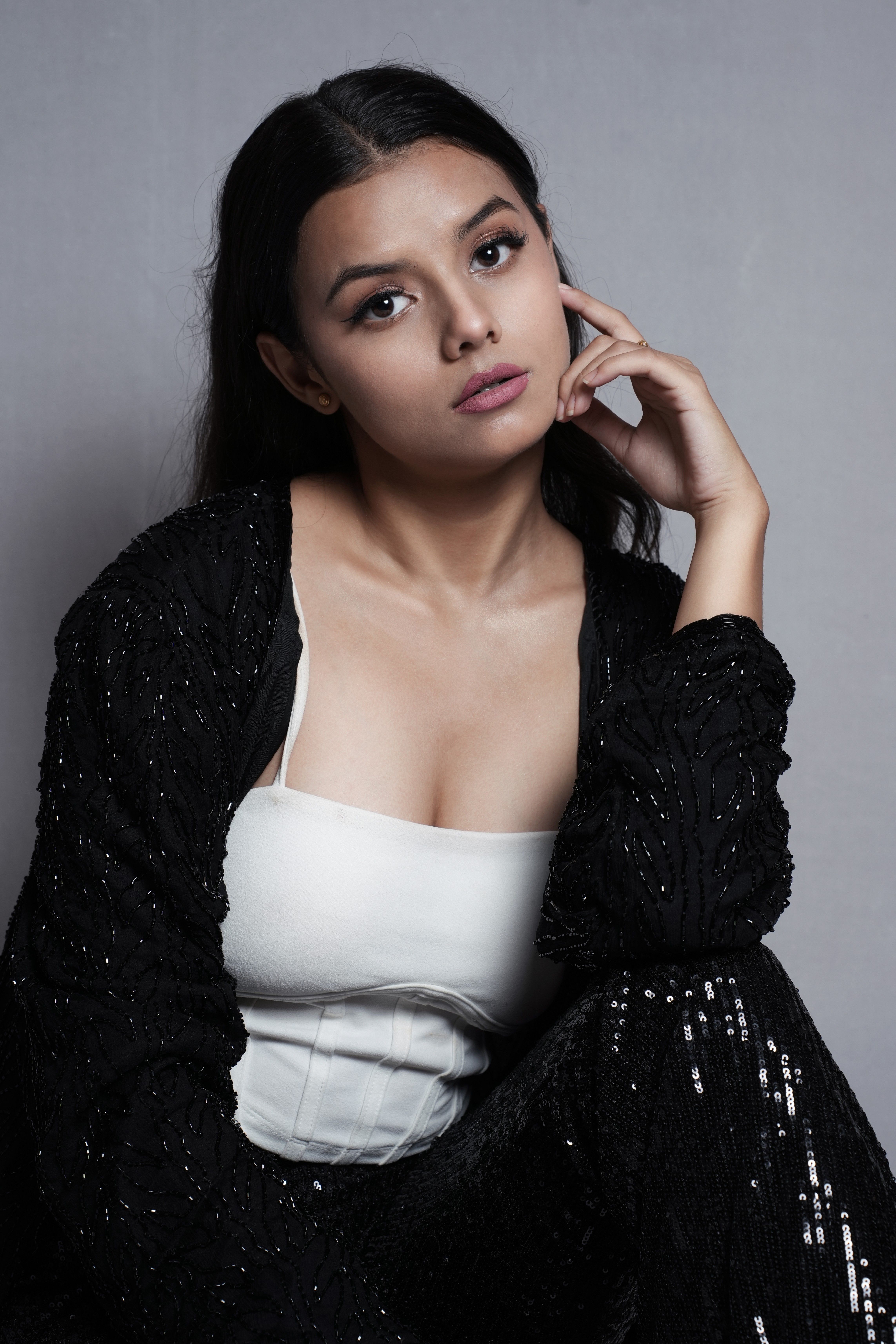 Editorial portrait of a woman in black and white clothing with her hand beside her face.