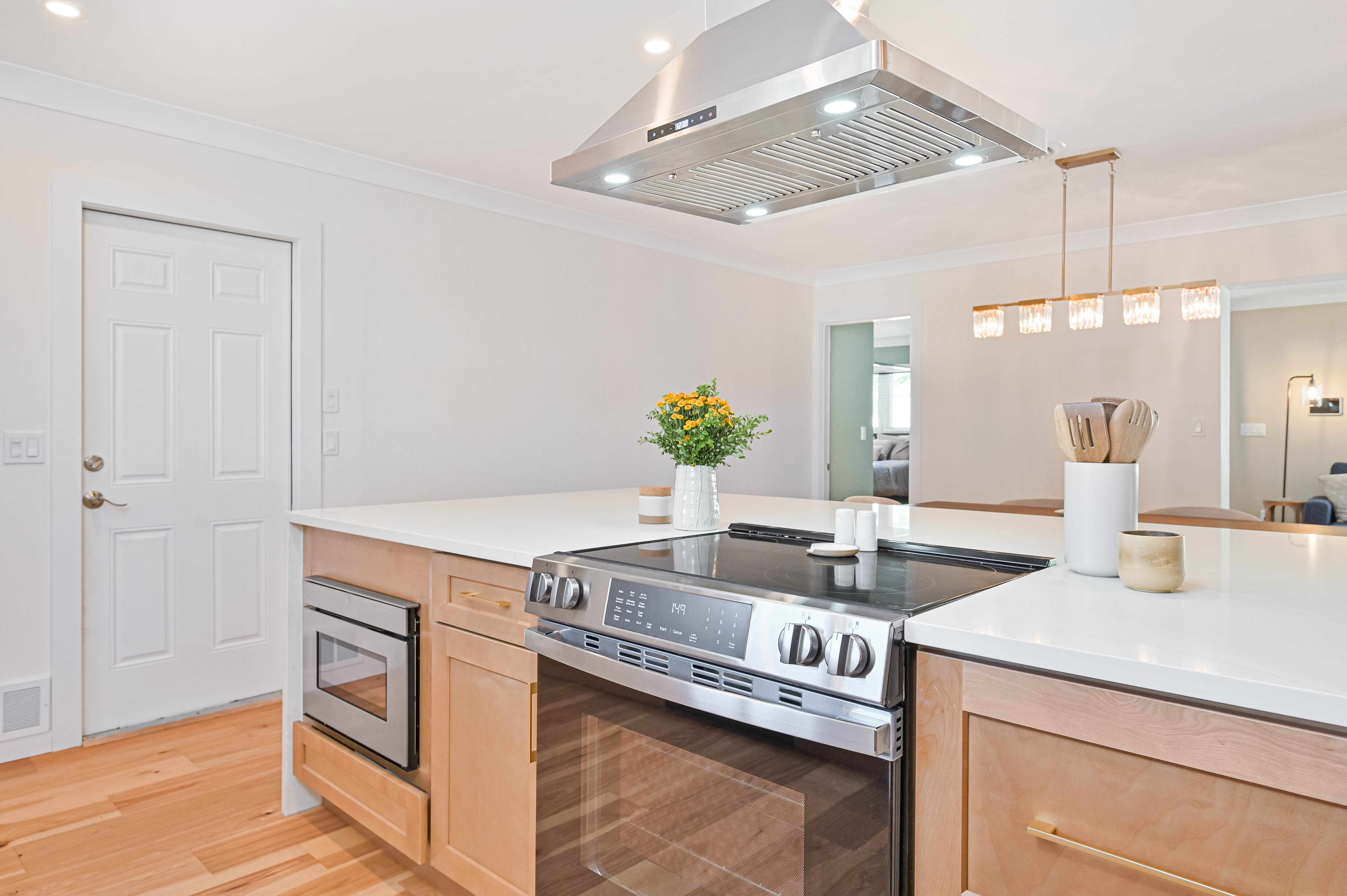 Schooner Bay Builders kitchen island cooktop with stainless range hood and custom wood drawers