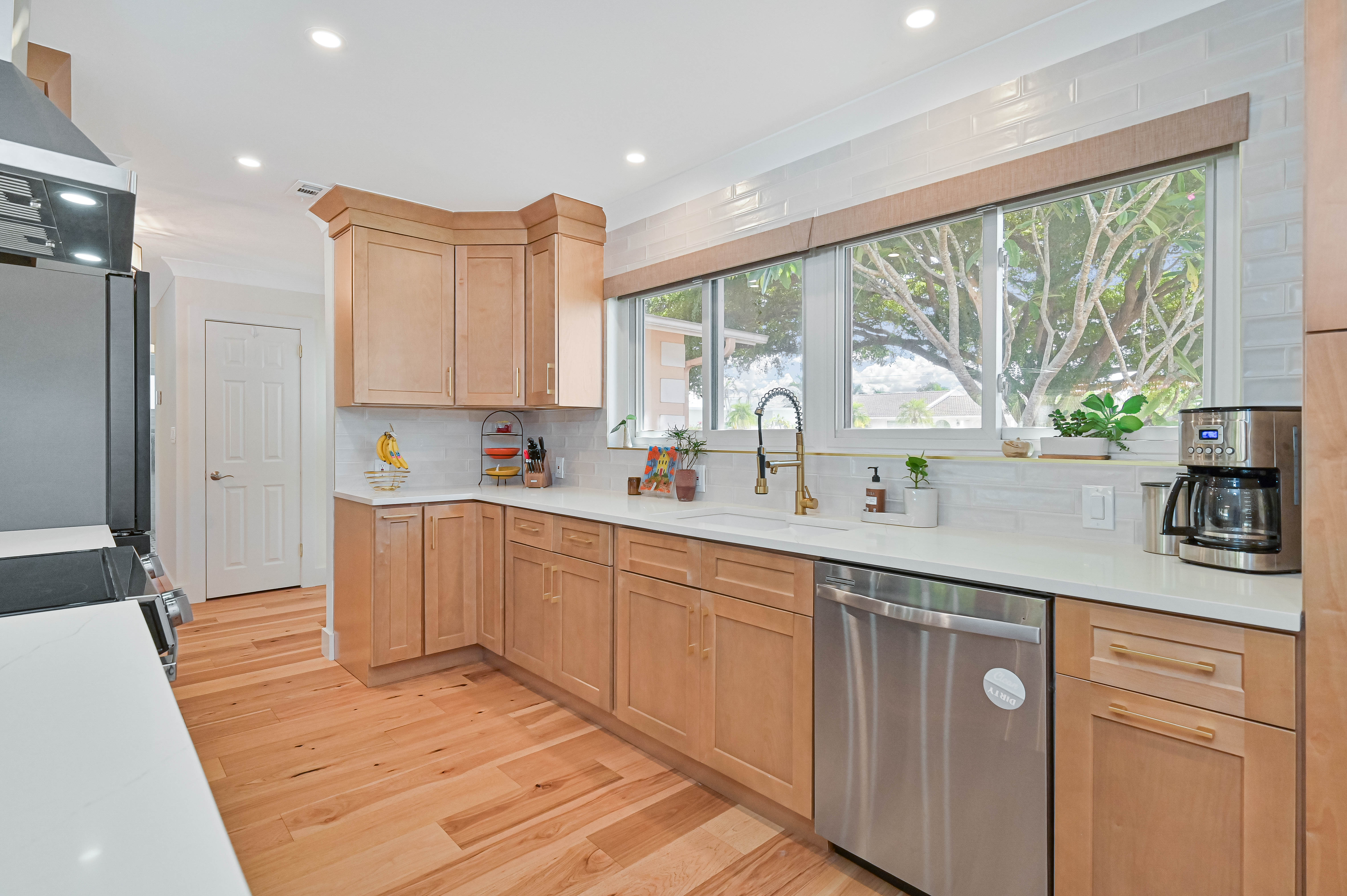 Schooner Bay Builders authentic kitchen perimeter with warm natural wood cabinetry, quartz countertop and stainless dishwasher