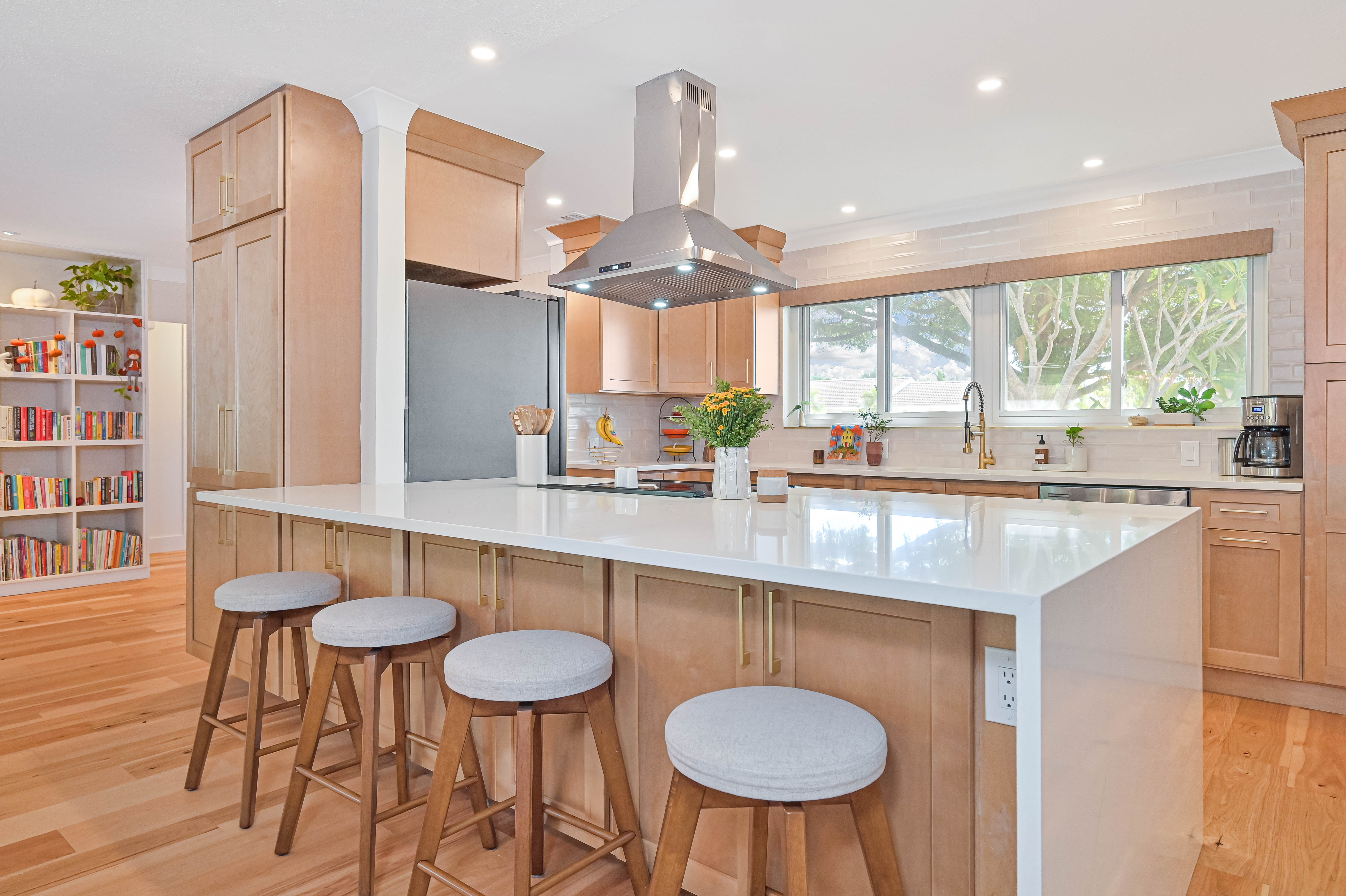 Schooner Bay Builders authentic kitchen remodel with custom island, waterfall quartz, modern barstools and warm wood cabinetry