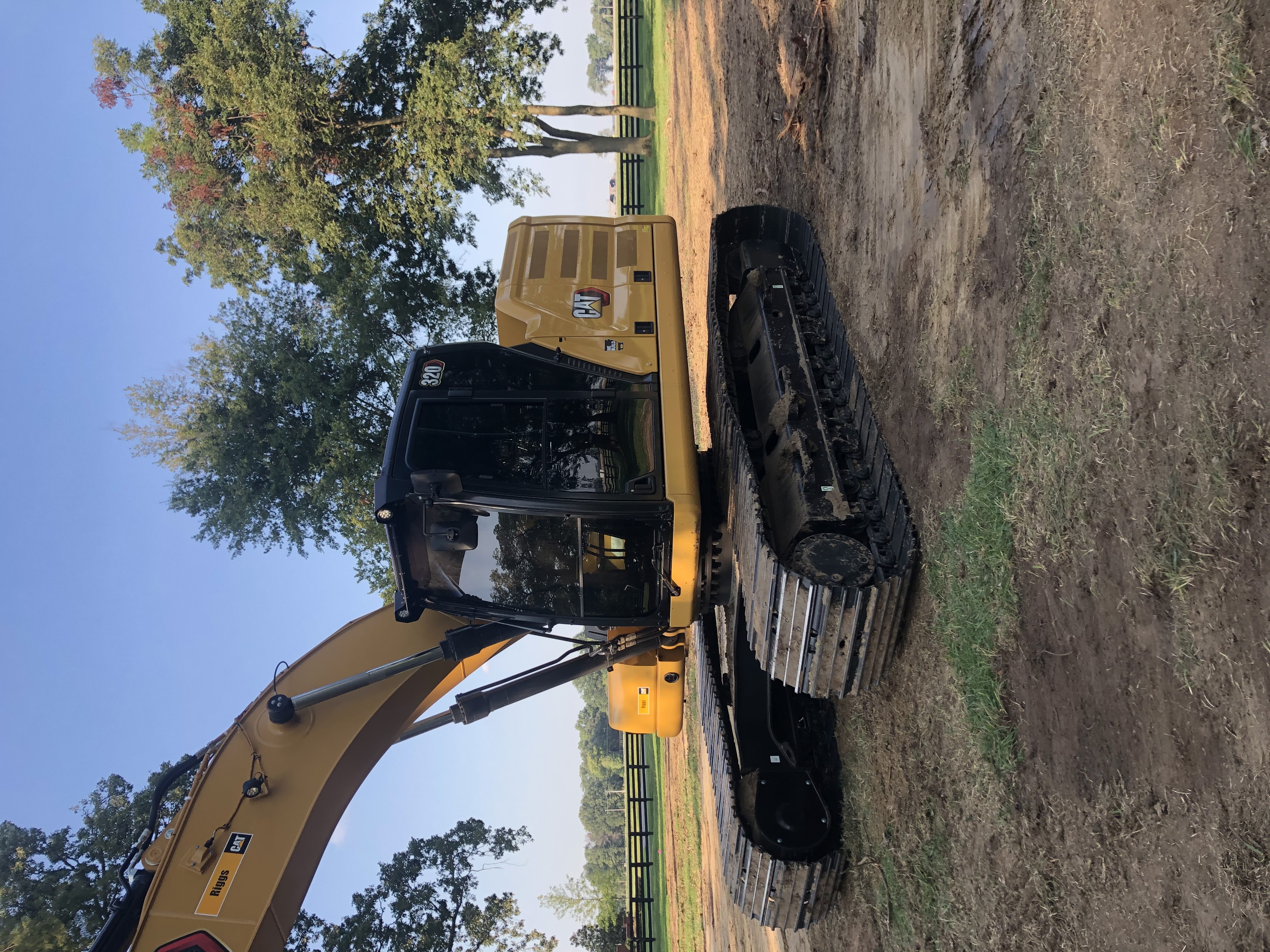Excavator clearing trees and vegetation to prepare a site