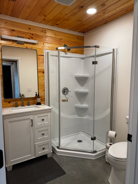 Groom's den private full bathroom with glass corner shower and white vanity at The Willow