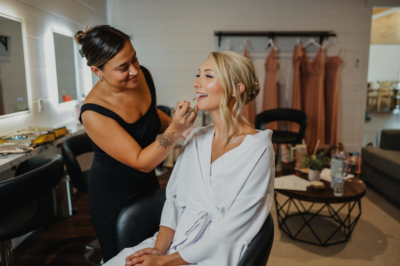 Bride in silk robe having wedding day makeup applied in the bridal preparation chair