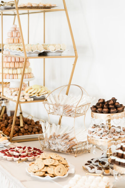 Elaborate wedding cookie table and dessert display with macarons, truffles, and tiered stands