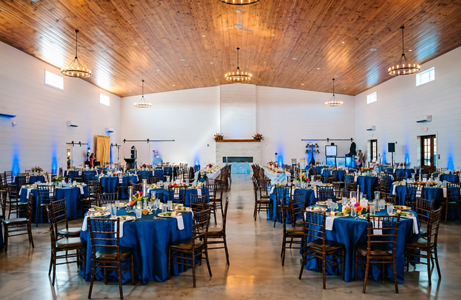 Grand hall at The Willow set with royal blue banquet round tables under vaulted wood ceiling