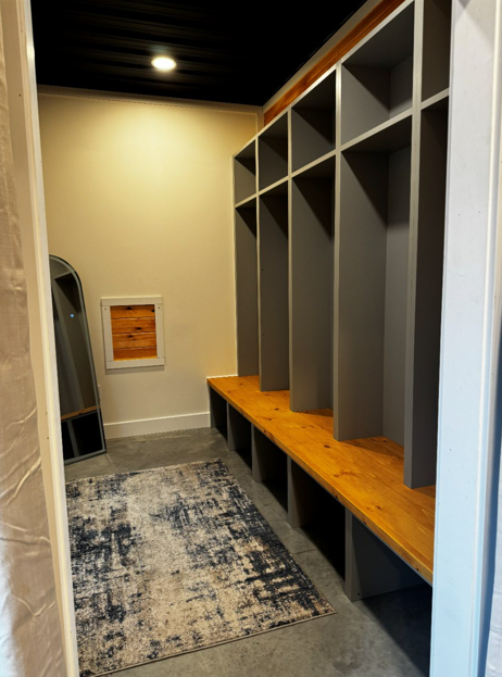 Groom's Den dressing lockers and wood bench seating with full-length mirror and rug