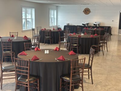 Spacious Side Room arranged with round banquet tables, red napkins, and buffet station