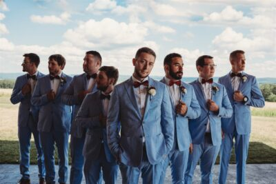 Groom and groomsmen in matching sky blue suits and burgundy bowties standing on patio overlooking Laurel Highlands