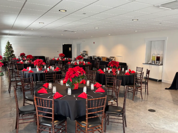 Holiday corporate banquet room with black tablecloths and vibrant red poinsettia centerpieces