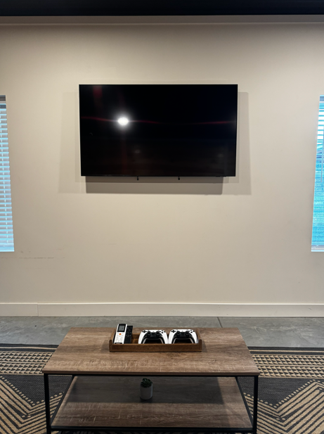 Groom's Den entertainment wall with mounted flat screen television, gaming console controllers, and coffee table at The Willow