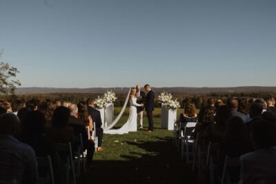 Evening wedding ceremony overlooking scenic mountain ridges and floral pedestals
