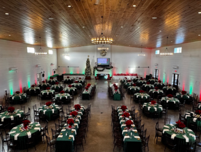 Grand ballroom configured for a large holiday corporate banquet with green linens and festive uplighting