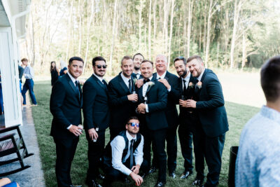 Groom and groomsmen smiling together on the lawn beside the patio