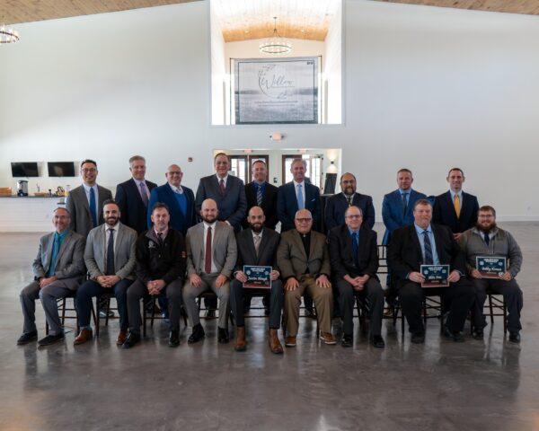 Corporate team award recipients and business group portrait in front of The Willow banner