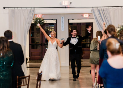 Newlyweds grand reception entrance through draped doorway with cheering guests