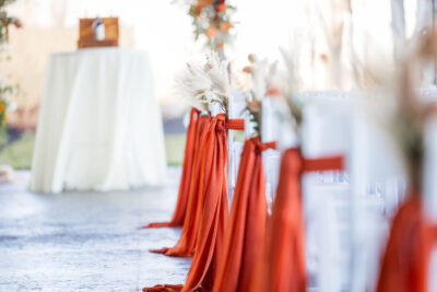Ceremony chair row detail on patio with burnt orange satin ribbons and pampas grass