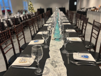 Close-up of winter holiday banquet table setting with teal glass tree centerpieces and frosted cookies in the Side Room