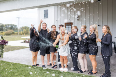 Bridal party celebrating and popping champagne on the patio grounds