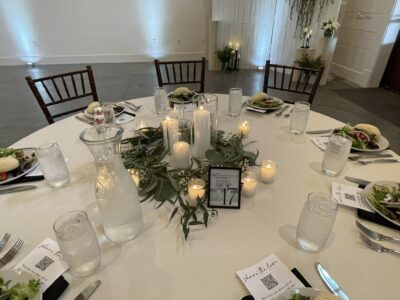 Reception tablescape detail with pillar candles, eucalyptus garland wreath, and place settings