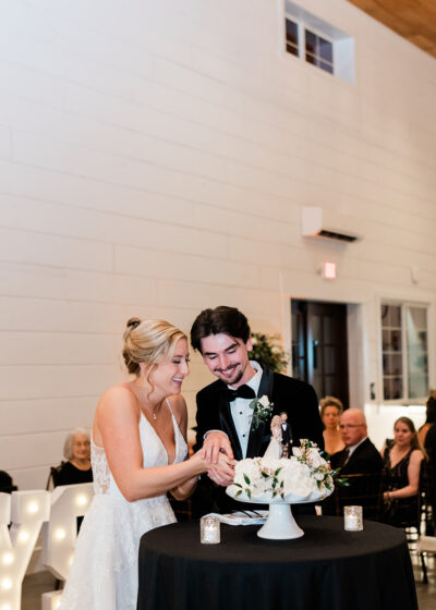 Bride and groom cutting their wedding cake together in front of illuminated LOVE marquee letters