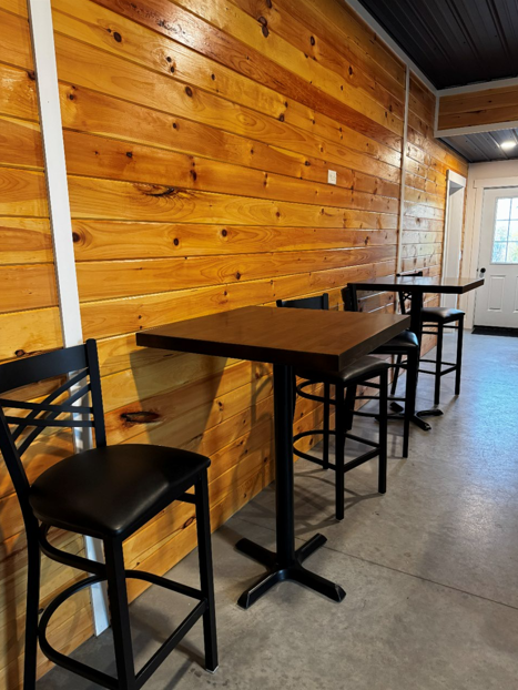 Groom's Den high-top pub tables and leather barstools along natural wood shiplap accent wall