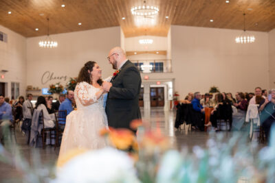Bride and groom first dance under grand chandelier in reception hall during fall wedding