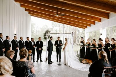 Spring wedding ceremony under covered timber patio with bridal party and guests