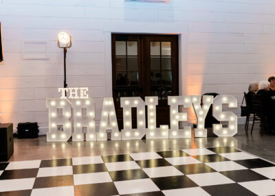 Illuminated marquee letters spelling The Bradleys in front of checkered dance floor at The Willow