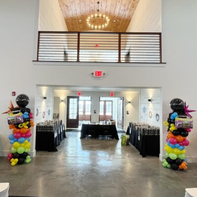 Mezzanine and hall entryway decorated with colorful retro boombox balloon pillars for a themed social event